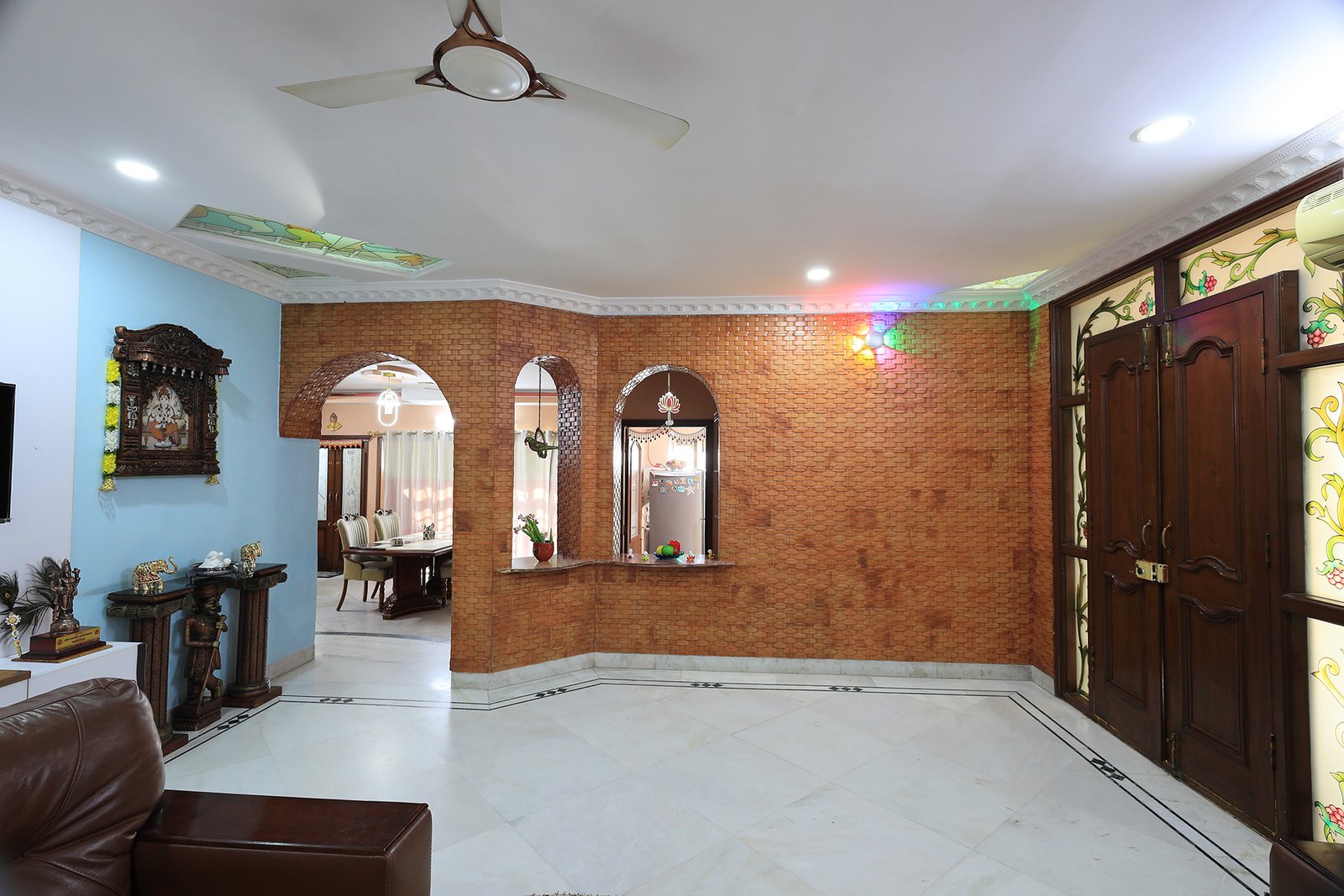 Wide view of the living room opening through brick archways to the dining room and kitchen