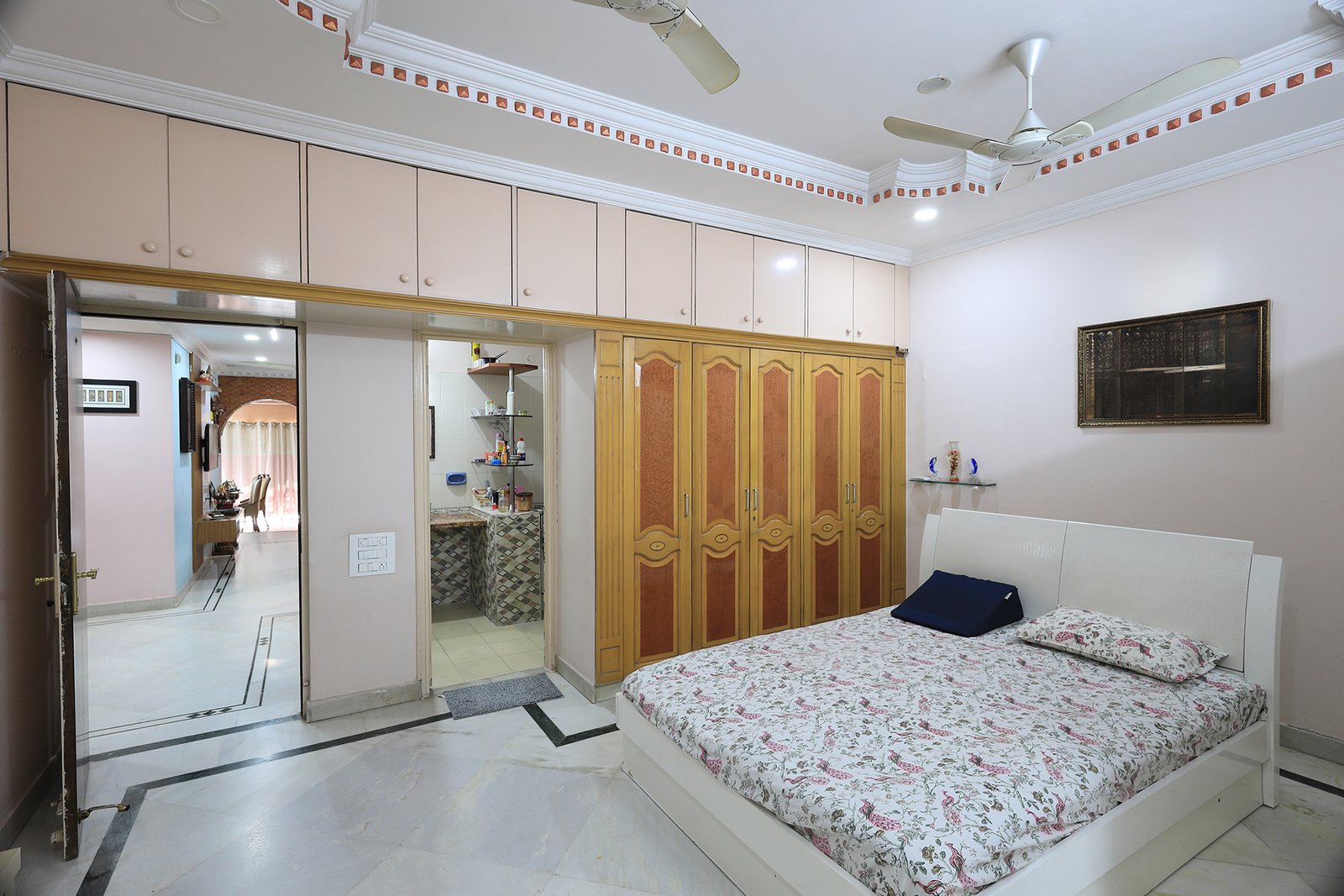Master bedroom with wooden wardrobes, overhead storage cabinets, and the attached bathroom
