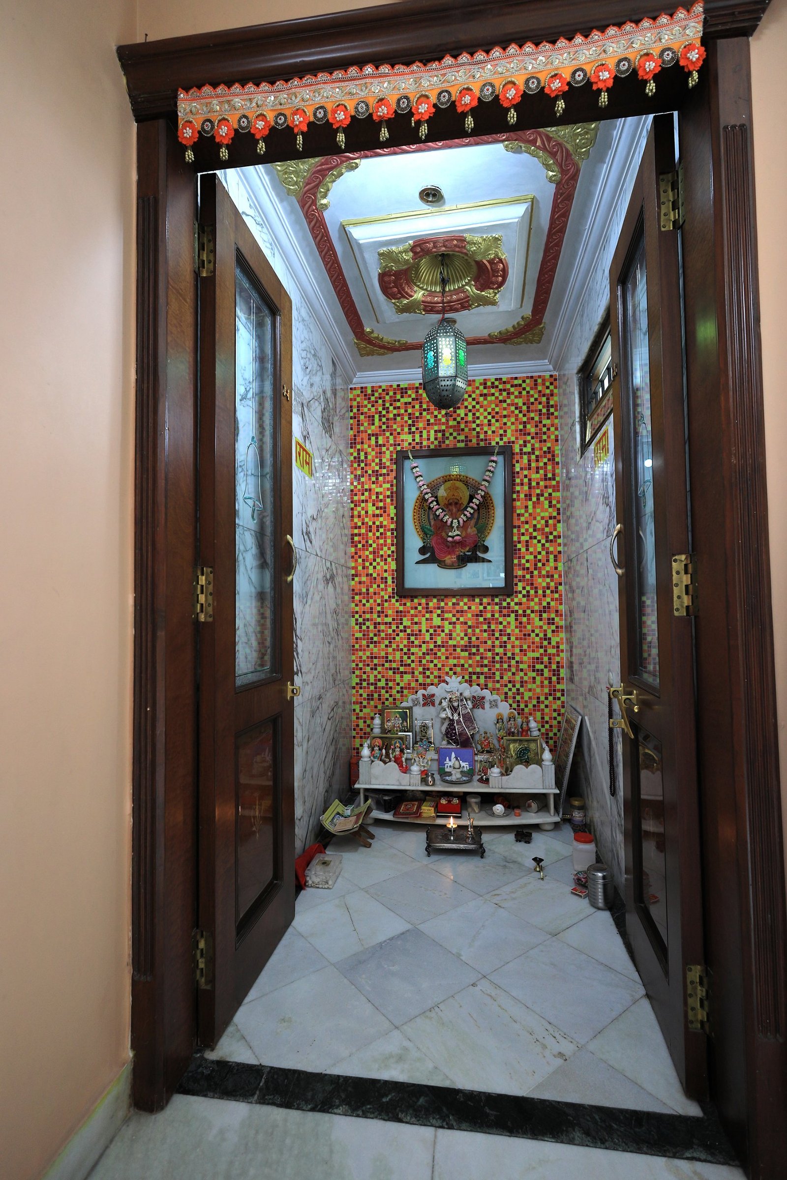 Dedicated pooja room with marble flooring, mosaic feature wall, and ornate ceiling